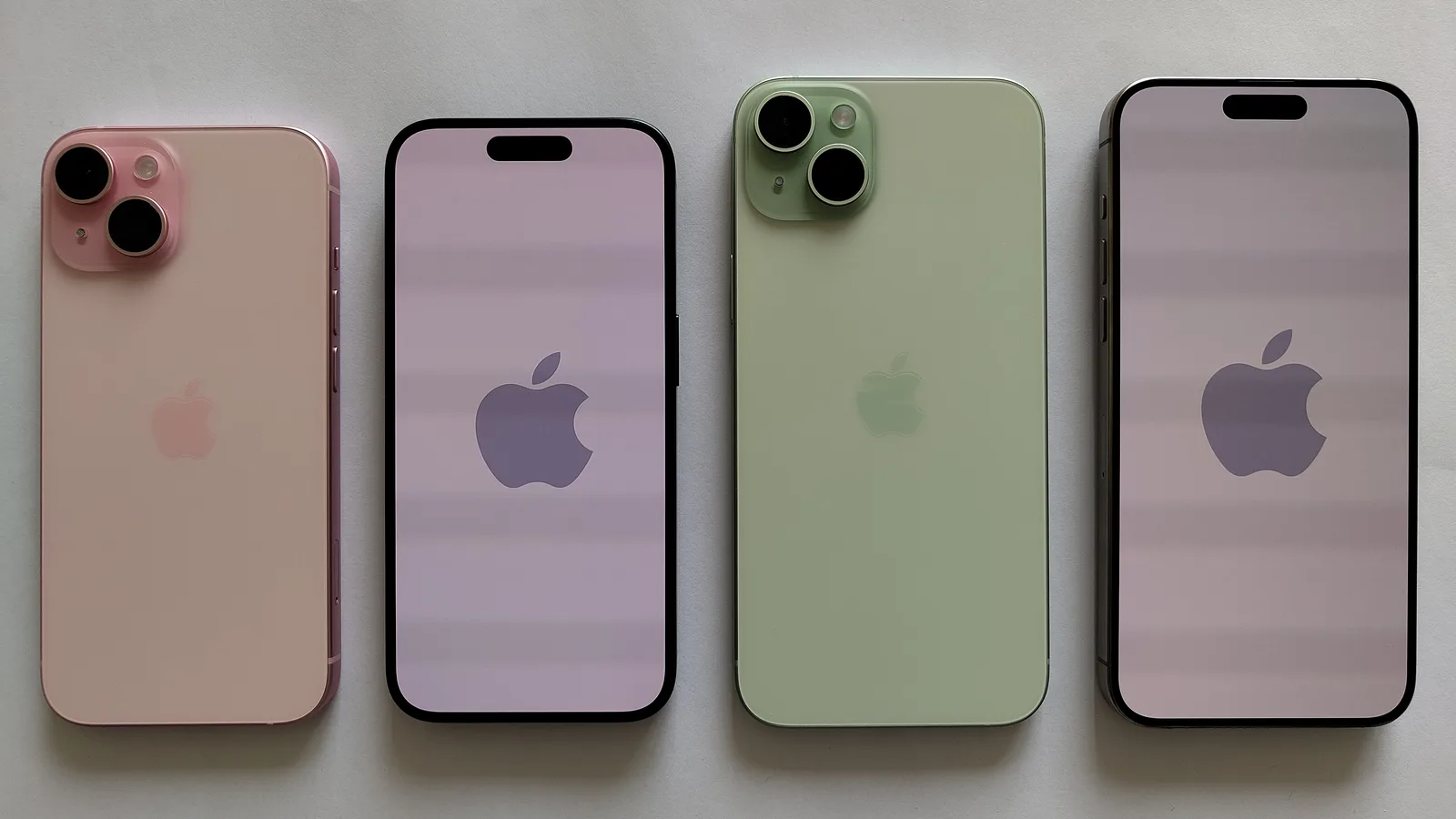 Empat iPhone diletakkan sebelah-menyebelah di atas permukaan kelabu polos: satu merah jambu dan satu hijau menunjukkan bahagian belakang dan dua kameranya, dan dua lagi menunjukkan skrin dengan logo Apple