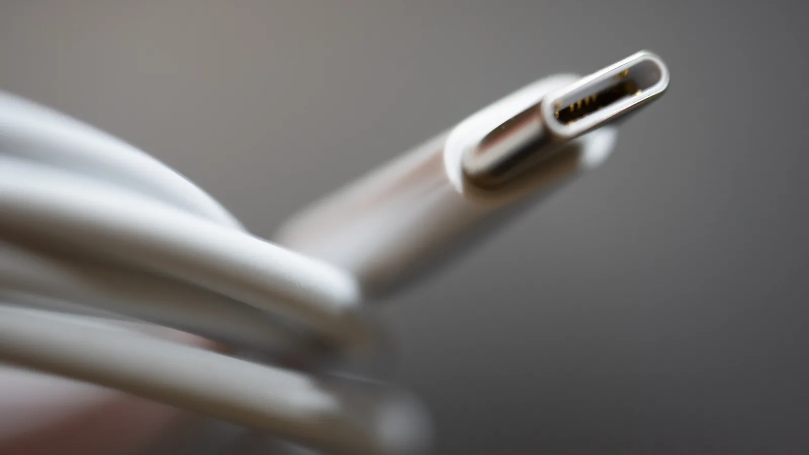 白色充电线上金属 USB-C 接头的特写，后方是盘绕的线缆