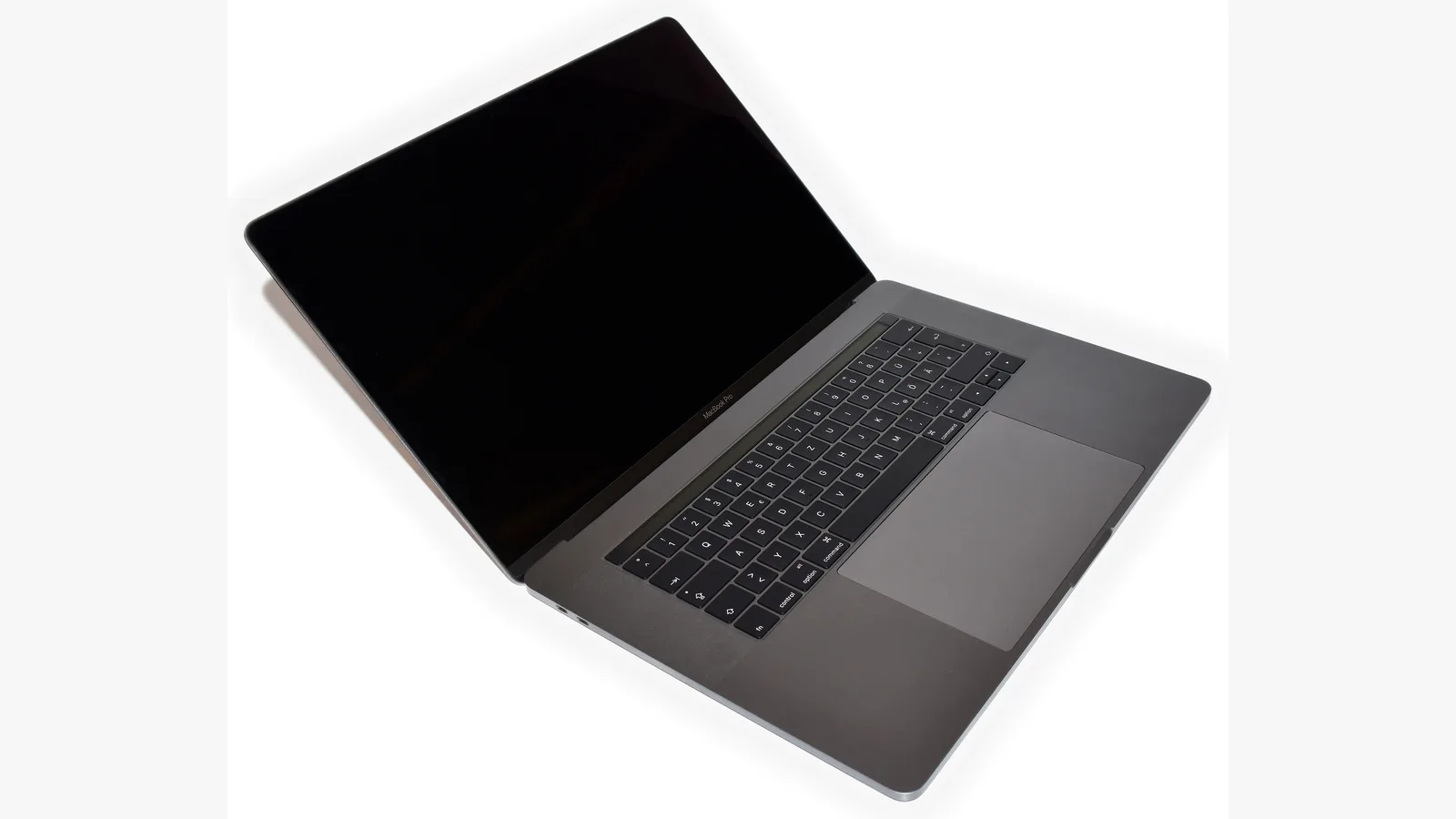 Sebuah MacBook Pro kelabu angkasa terbuka pada sudut di atas latar putih, skrinnya gelap dan dimatikan, papan kekunci dan pad sentuh kelihatan