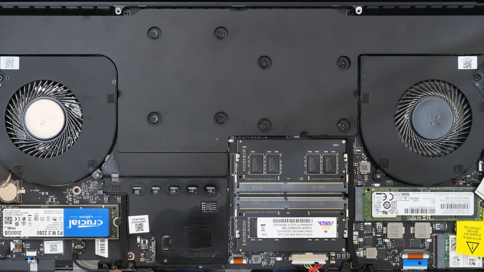 A laptop with its base cover removed, showing two cooling fans, two memory sticks in their slots and two M.2 SSDs