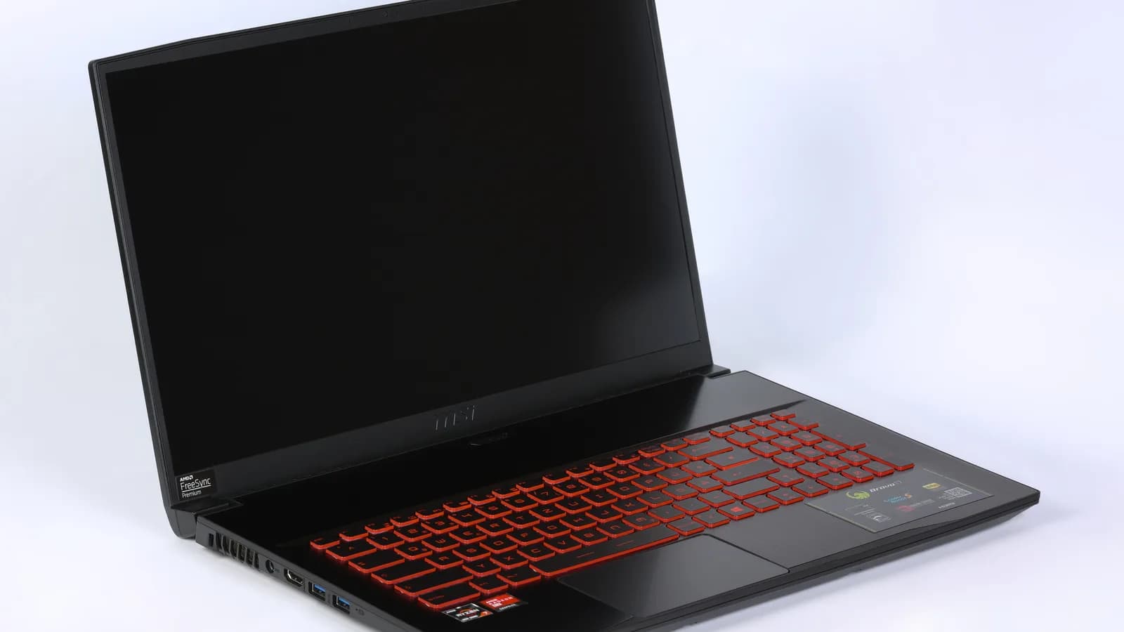 An open black MSI laptop on a white background, its screen dark and its keyboard backlit in red.