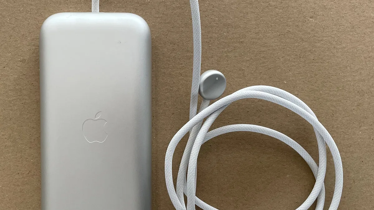 The external battery pack of an Apple Vision Pro beside a coiled white charging cable