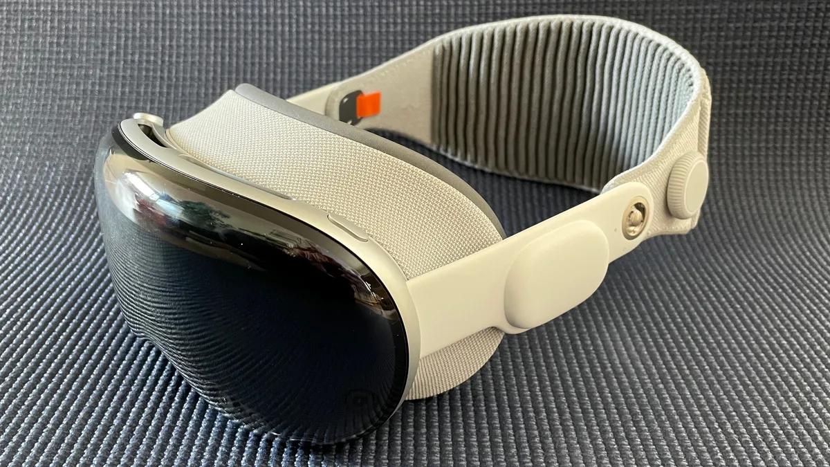 An Apple Vision Pro seen in profile from the left, showing its curved glass front