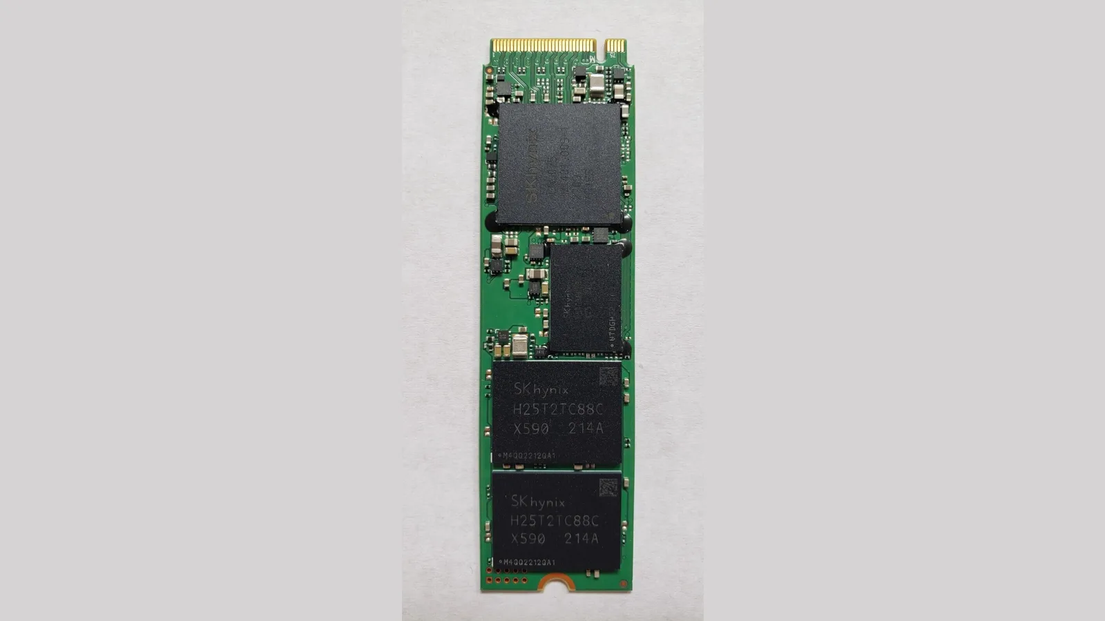 Papan pemacu keadaan pepejal M.2 NVMe berwarna hijau dengan beberapa cip memori SK hynix dan penyambung bertepi emas, di atas latar kelabu cerah