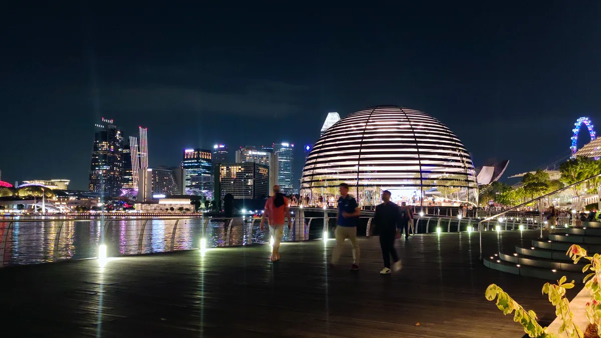 The same Apple Marina Bay Sands store at night, with customers walking in — take an active plan here first