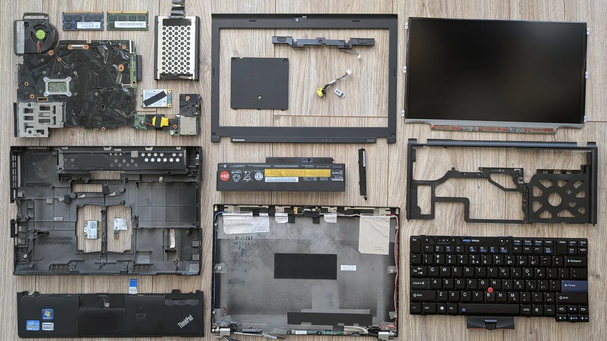 A Lenovo ThinkPad X220 taken completely apart, every component laid out in rows — screen panel, keyboard, battery, motherboard and chassis