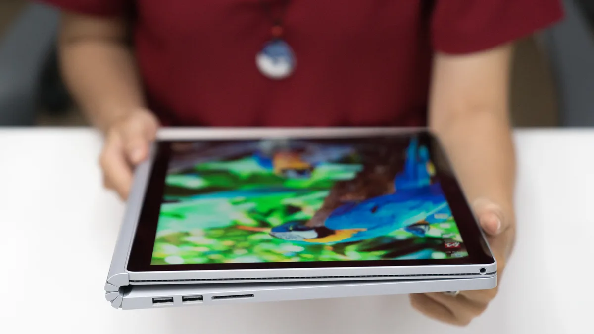 平举的 Microsoft Surface Book 2,屏幕向后翻折覆盖在键盘上