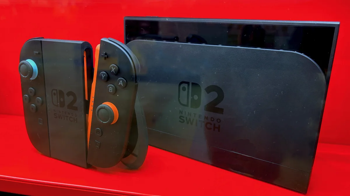 A Nintendo Switch 2 console standing upright with its two Joy-Con 2 controllers detached and propped beside it