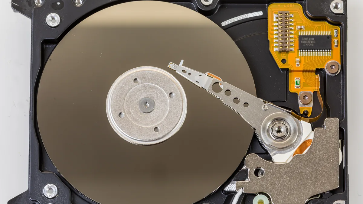 A laptop hard disk with its cover removed, exposing the platter and read-write head inside