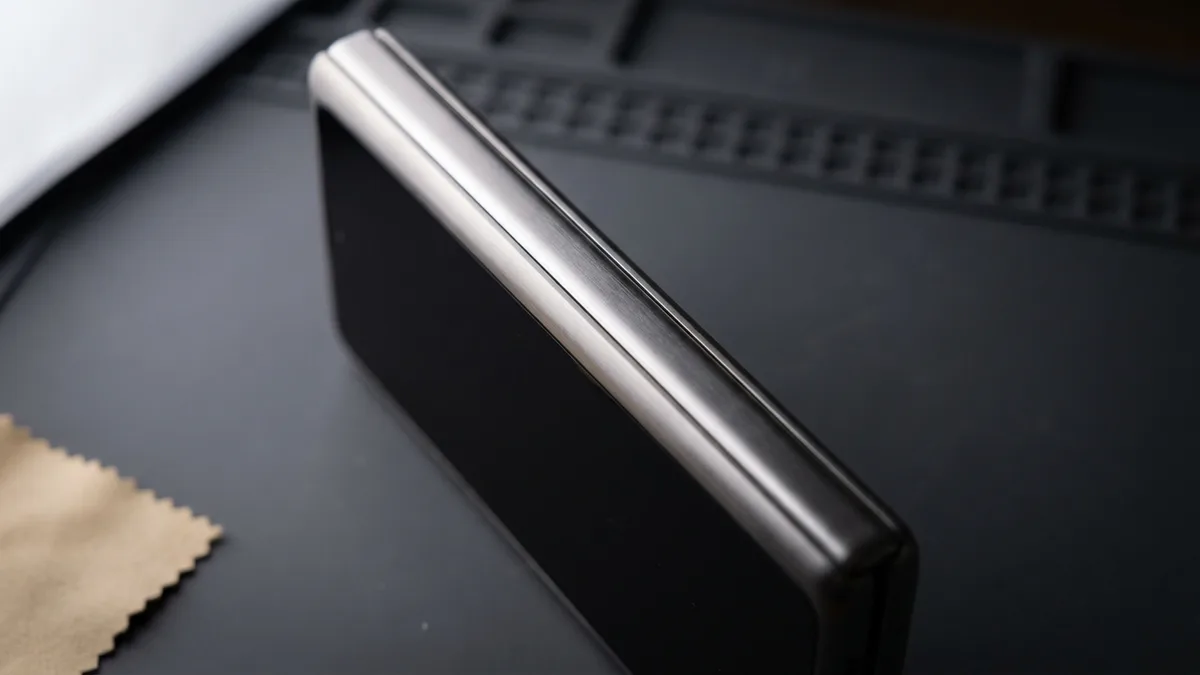 Macro along the closed hinge spine of a folding phone, the two halves shut to a hairline with no gap