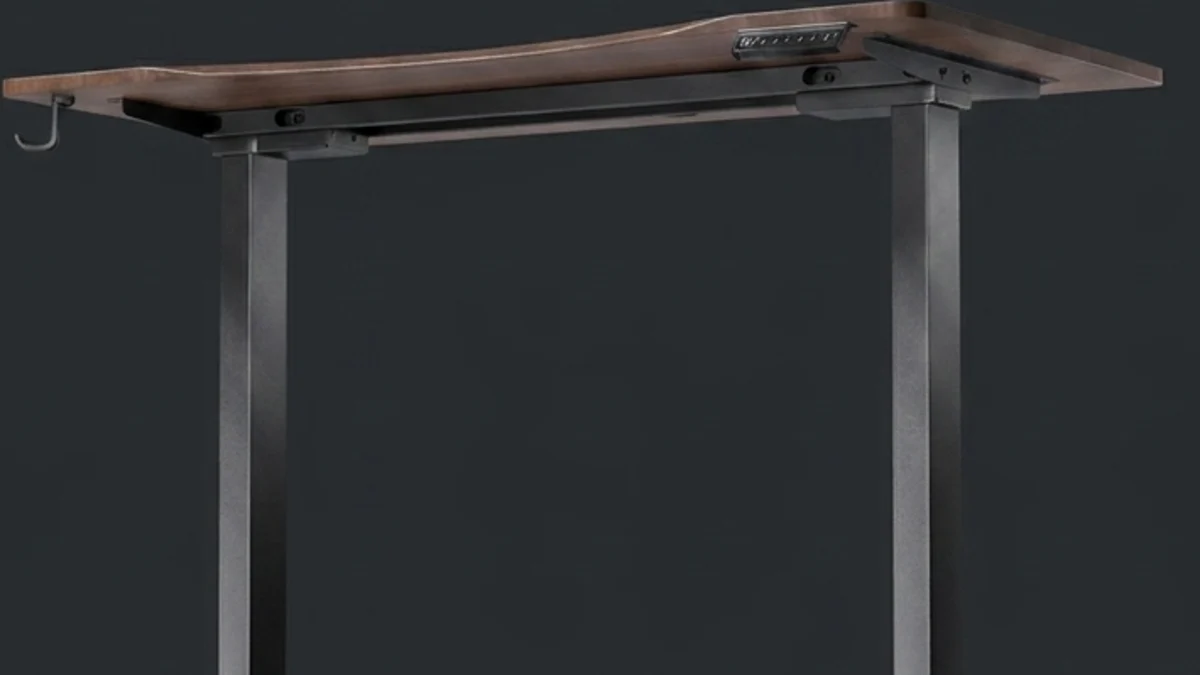 The underside of the Vival desk seen from the side, showing the black steel frame rails bolted across the tabletop, the mounting brackets and bolt heads, the cable hook at the left and the two leg columns.