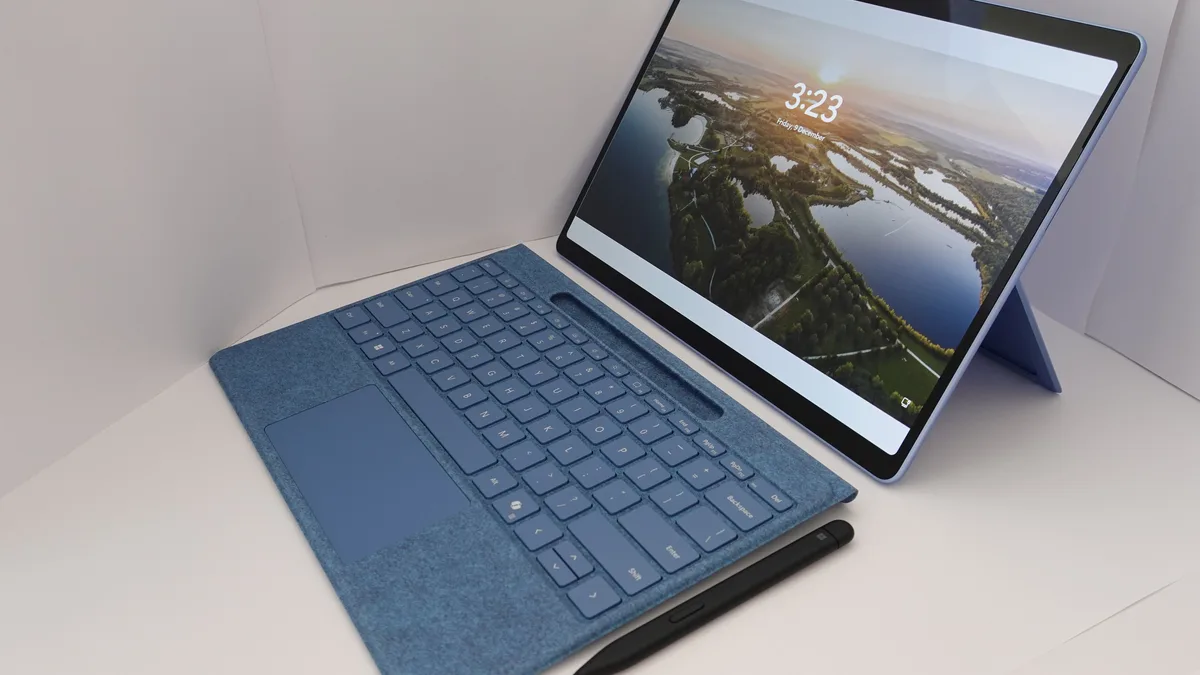 Sebuah tablet Windows boleh tanggal moden dengan penutup papan kekunci dan stilusnya di sebelahnya