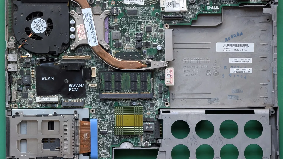 Komputer riba Windows lama dibuka di atas meja kerja: papan induk, kipas penyejuk dan slot memori kelihatan